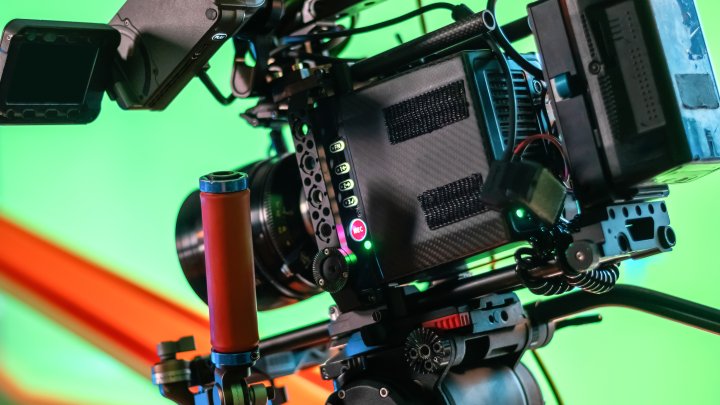 Professional video camera on the movie set with a lot of cables. Green screen on the background
